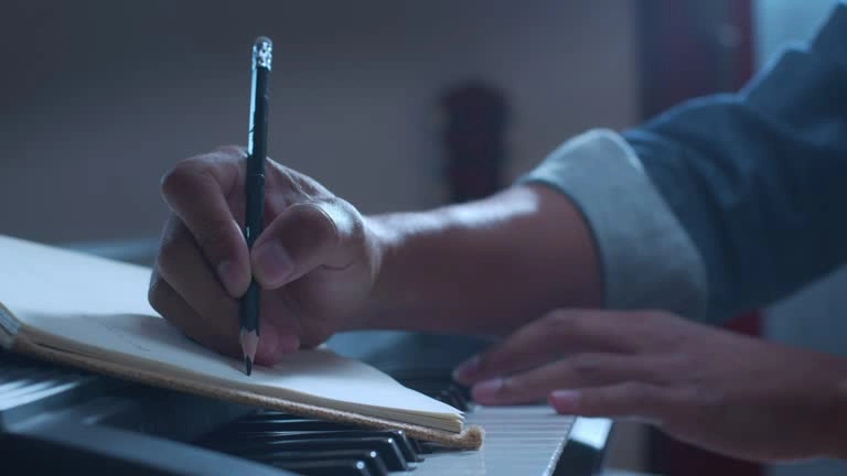 Close-up of writing on sheet music notebook resting on piano keys.