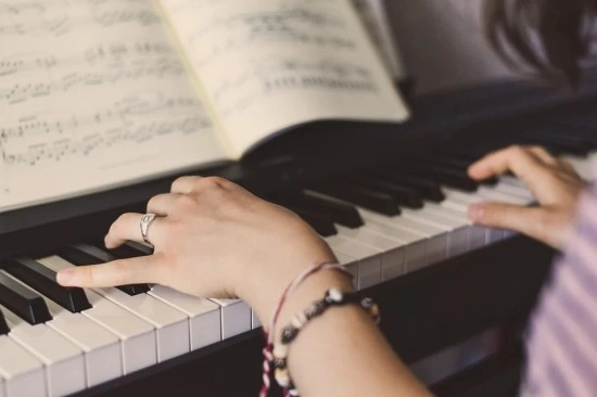 A pianist's hands playing on a grand piano with sheet music visible on the music stand.
