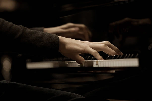 Close-up of pianist's hands playing on piano keys.