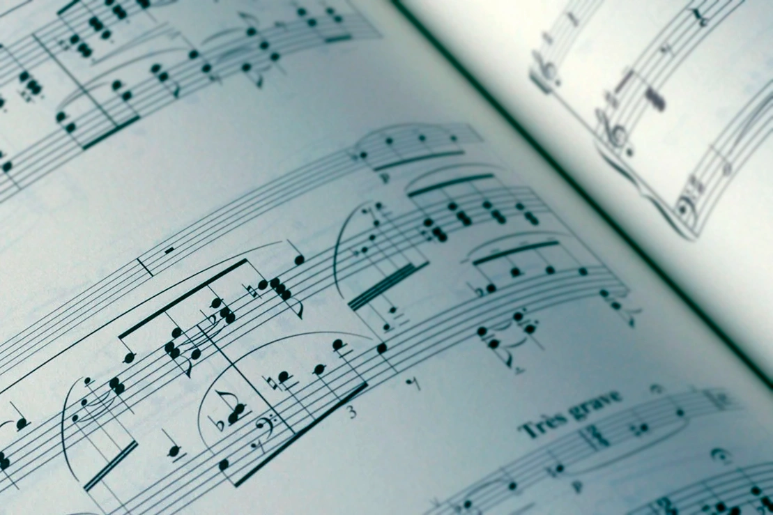 Close-up of a spread of printed sheet music showing musical notation.